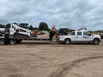 a pickup truck hauling an mini excavator 